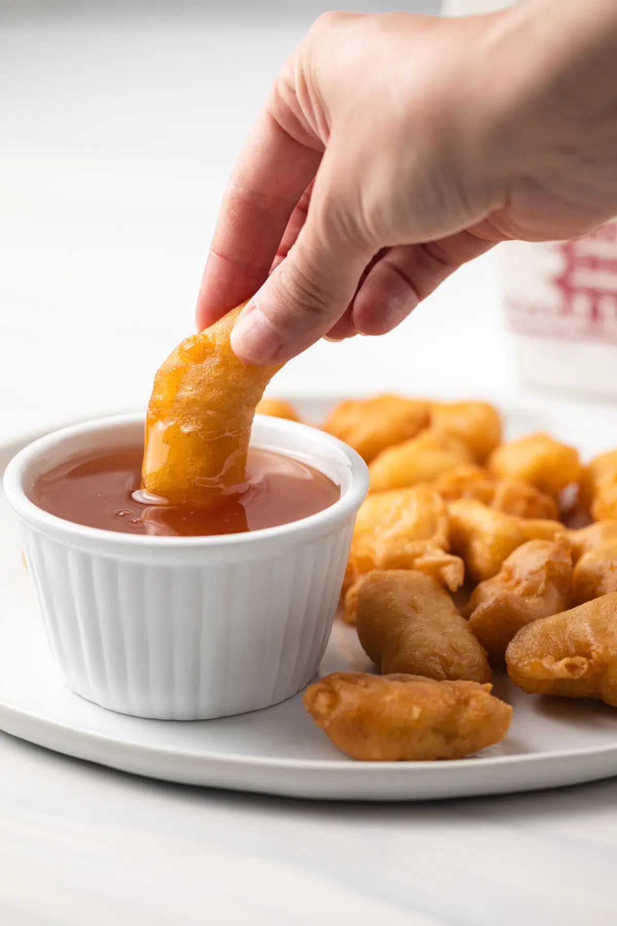 Dipping chicken into sweet and sour sauce.