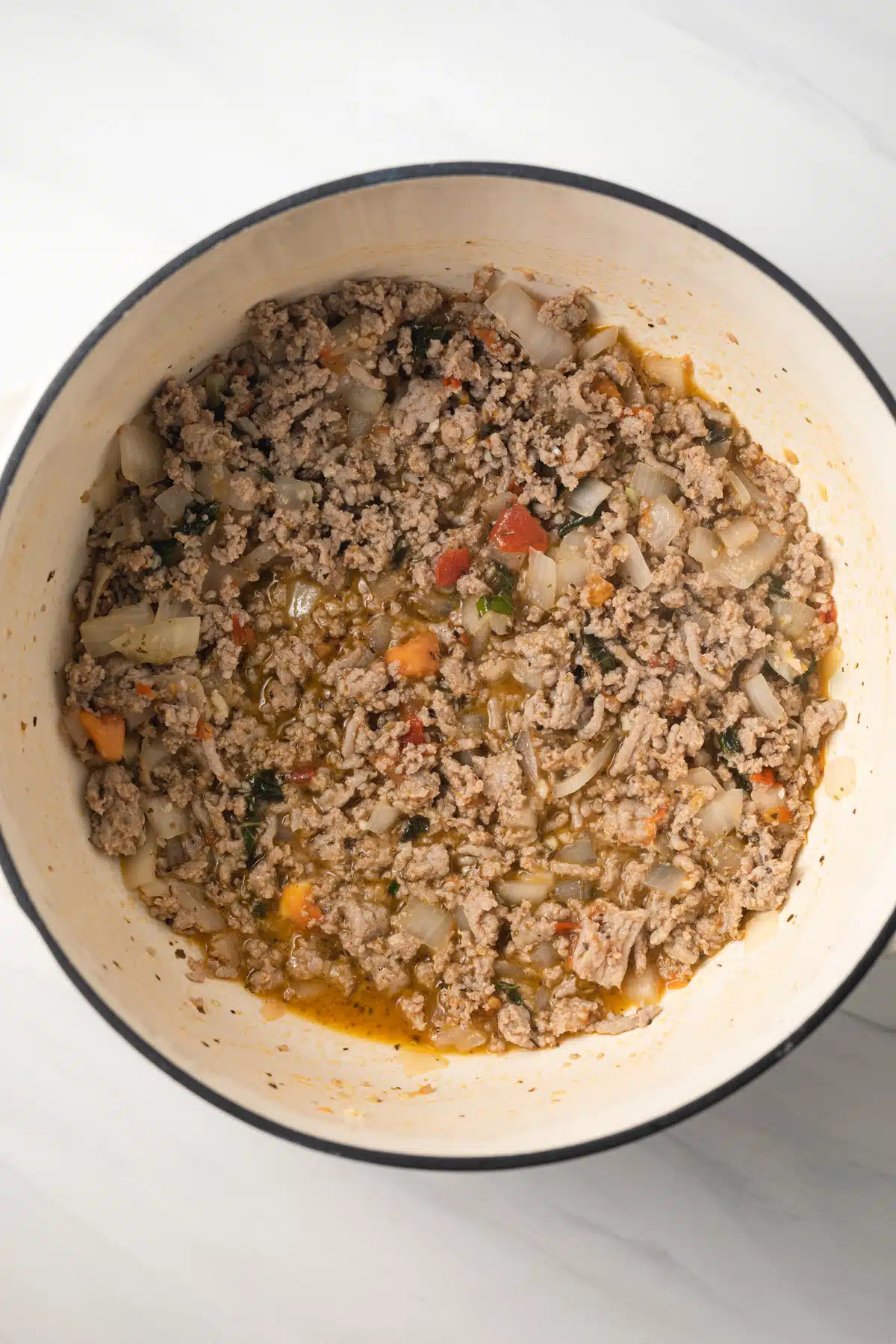 Ground turkey with spices and herbs in saucepan.