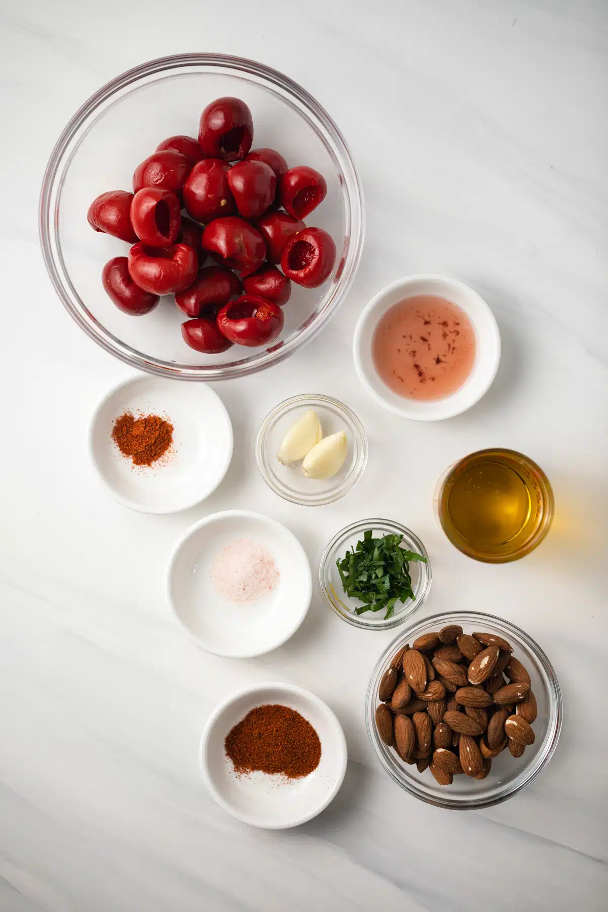 Ingredients for red pepper romesco in glass bowls.