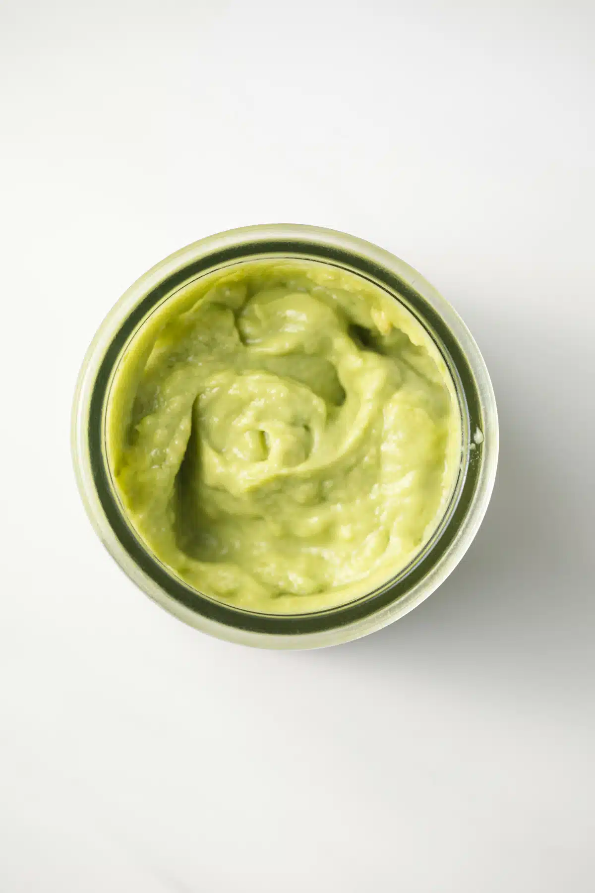 Overhead of avocado mayo in a glass jar.