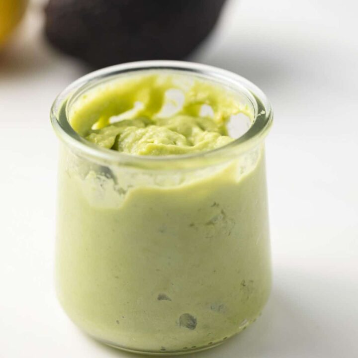 Side view of avocado mayo in glass jar.