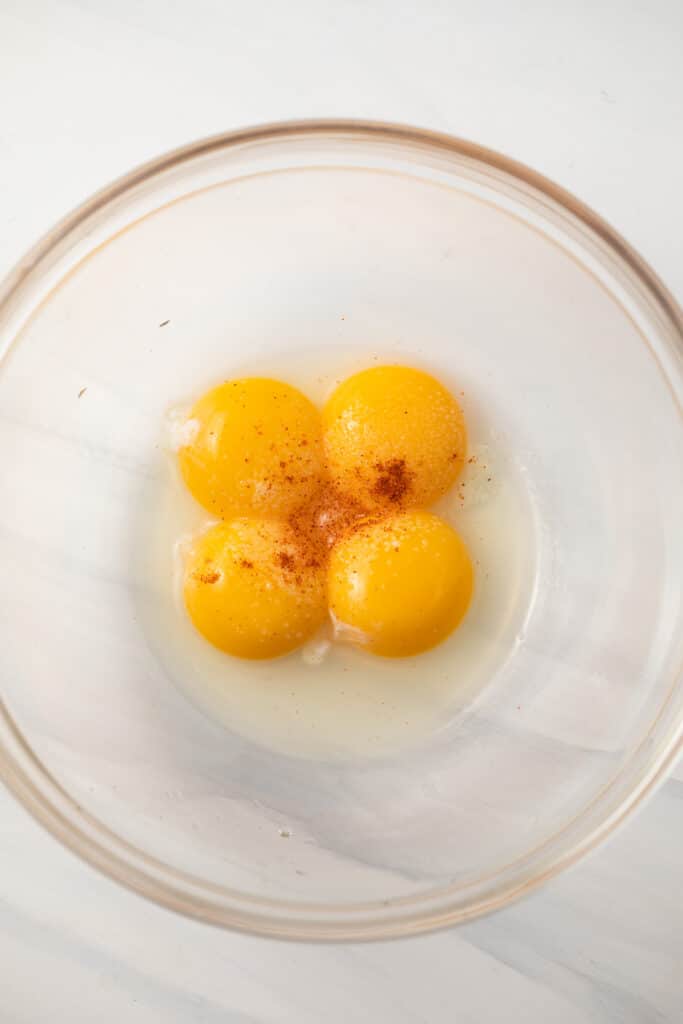 Egg yolks, lemon juice, salt, and cayenne pepper in glass bowl.