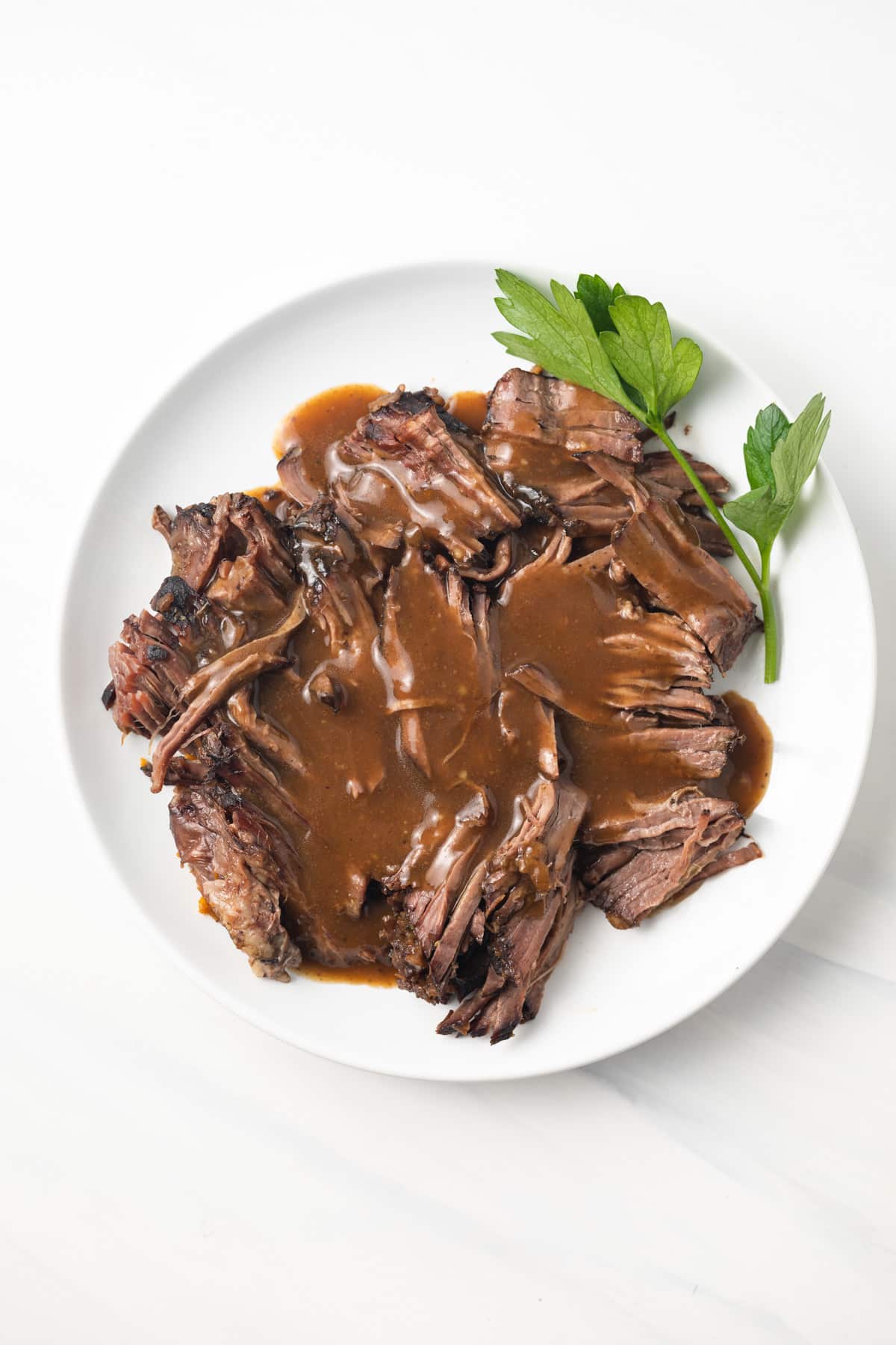 Overhead of pot roast gravy over shredded roast.