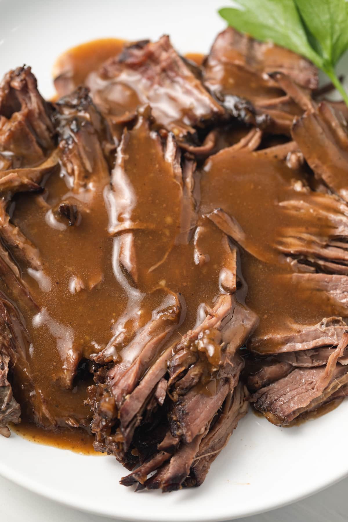 Close up of pot roast gravy over shredded roast.