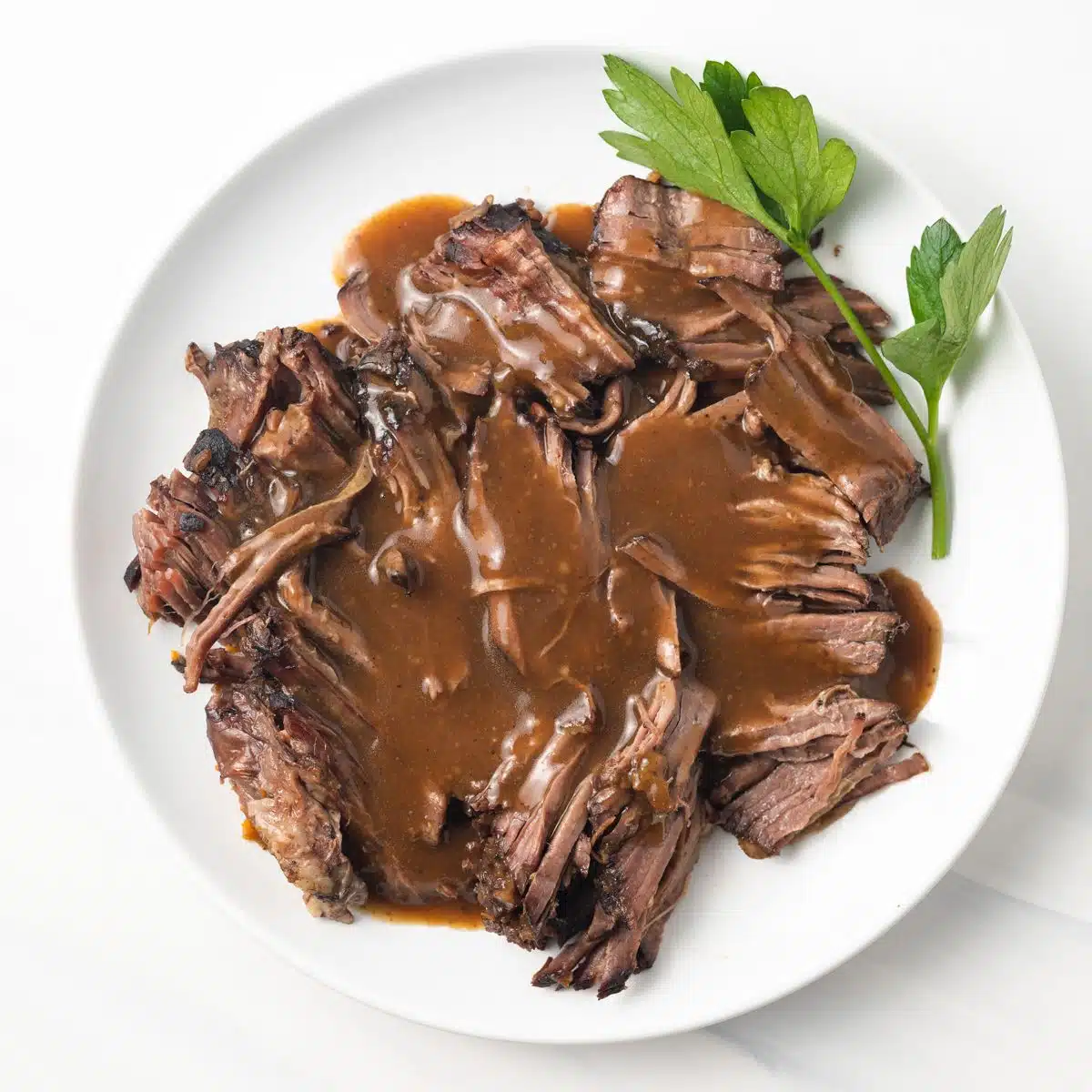 Overhead of pot roast gravy over shredded roast.