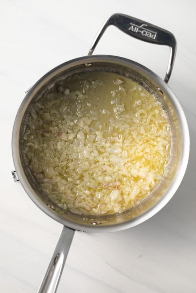 Shallots and garlic with melted butter in saucepan.