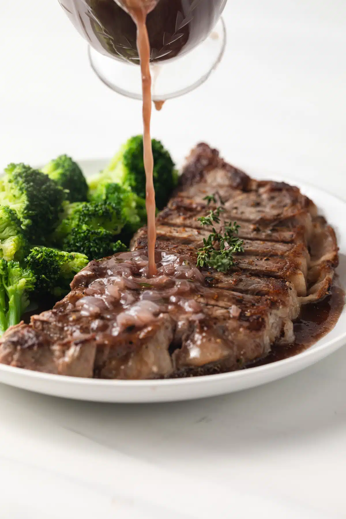 Pouring red wine sauce over steak.