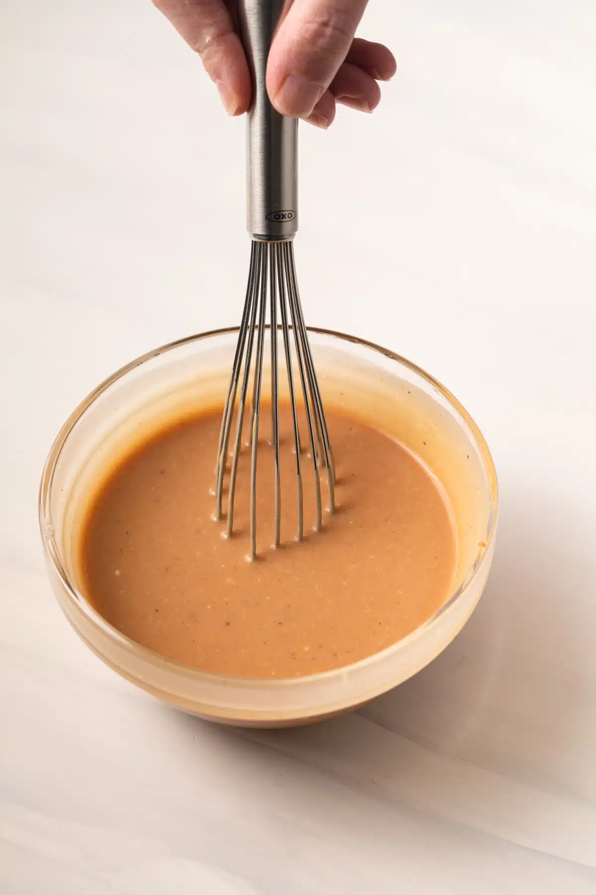 Mixing chicken nugget dipping sauce with a whisk.