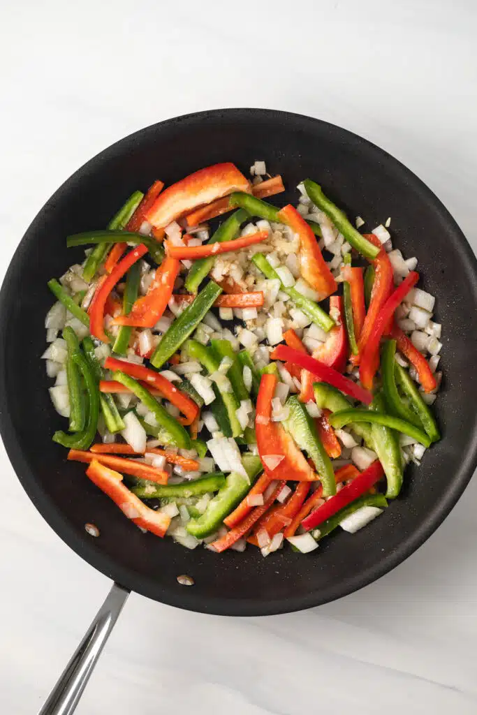 Bell peppers, onions, and garlic in a skillet.