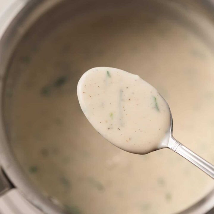 White garlic sauce on a spoon over a saucepan.