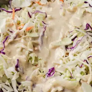 Coleslaw dressing poured over slaw.