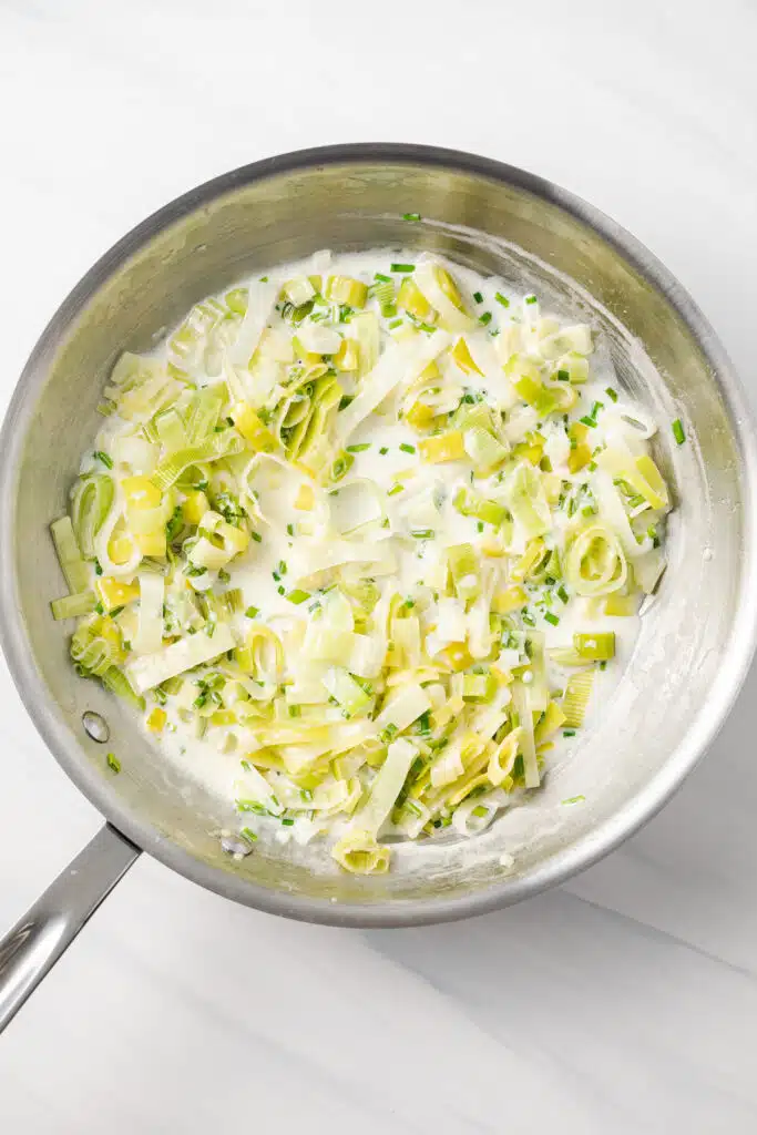 Sauteed leeks and cream in skillet.