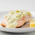 Creamy leek sauce over salmon with lemon wedge.