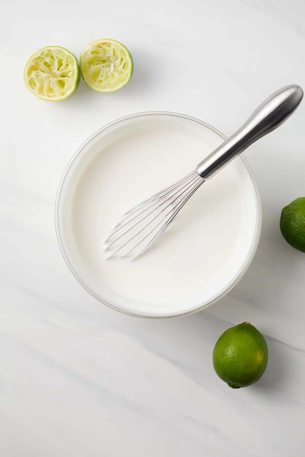 Ingredients for crema sauce whisked together in glass bowl.