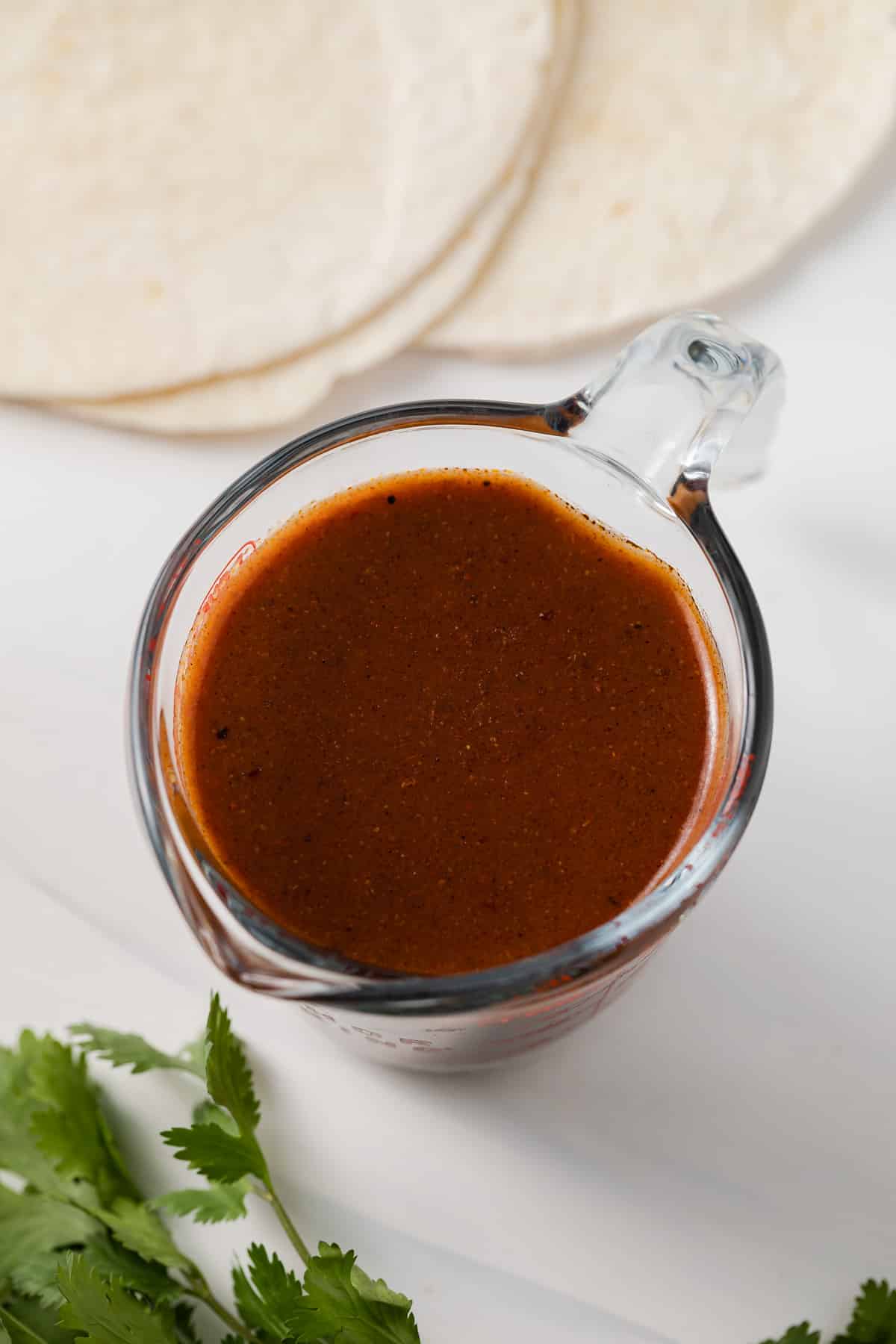 Red enchilada sauce in liquid measuring cup.
