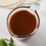 Red enchilada sauce in liquid measuring cup.