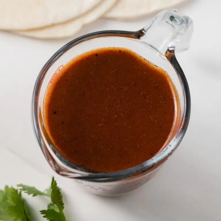 Red enchilada sauce in liquid measuring cup.