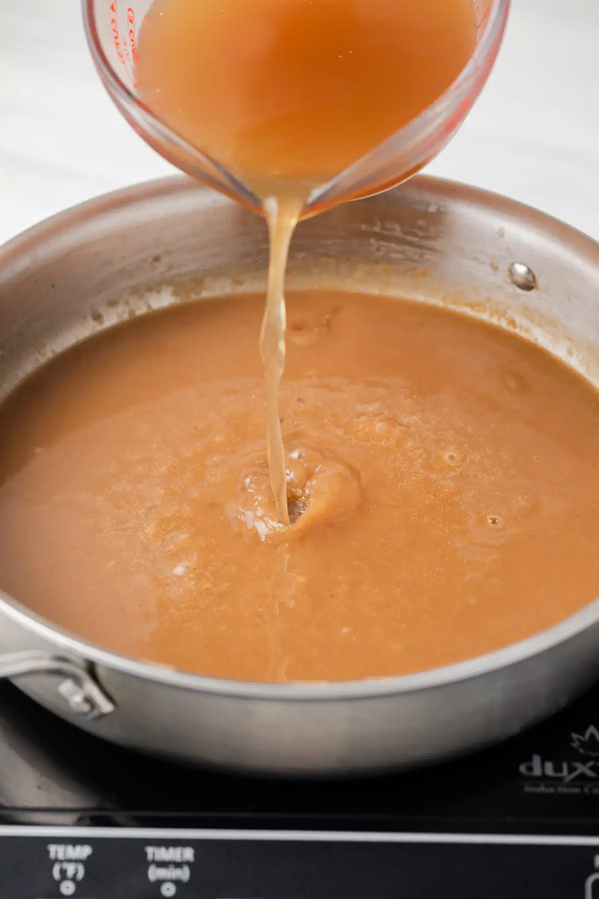 Broth being poured into brown roux.