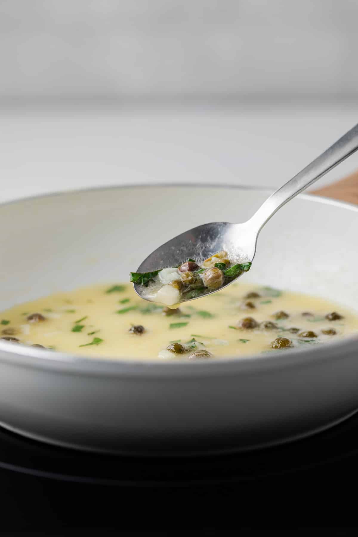 Lemon caper sauce on spoon.