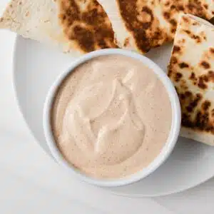 Overhead of quesadilla sauce in white bowl on plate with quesadillas.