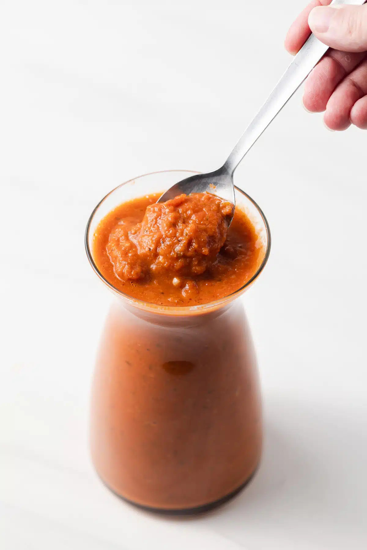 Spoon taking out ranchero sauce out of jar.