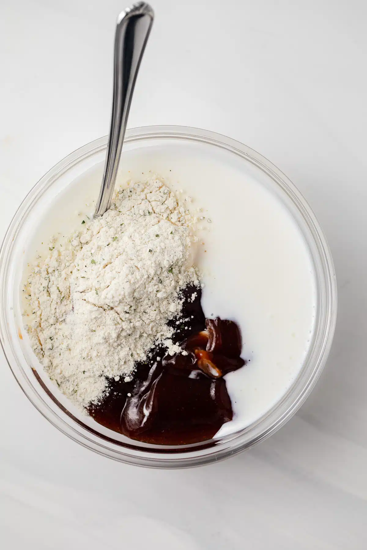 Ingredients for bbq ranch dressing combined in glass bowl.