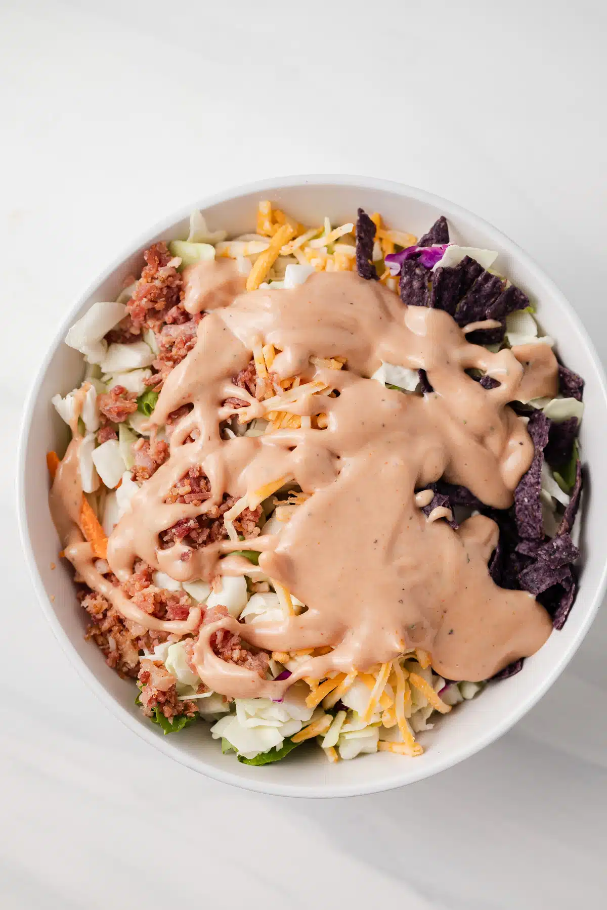 BBQ ranch dressing drizzled over salad in white bowl.