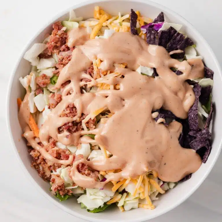 BBQ ranch dressing drizzled over salad in white bowl.