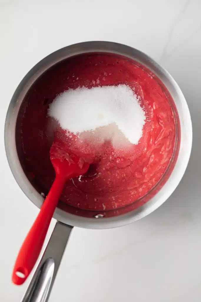 Pureed raspberries with sugar in a saucepan.