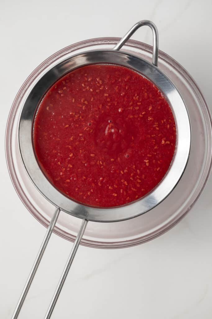 Raspberry Sauce in a fine mesh strainer.