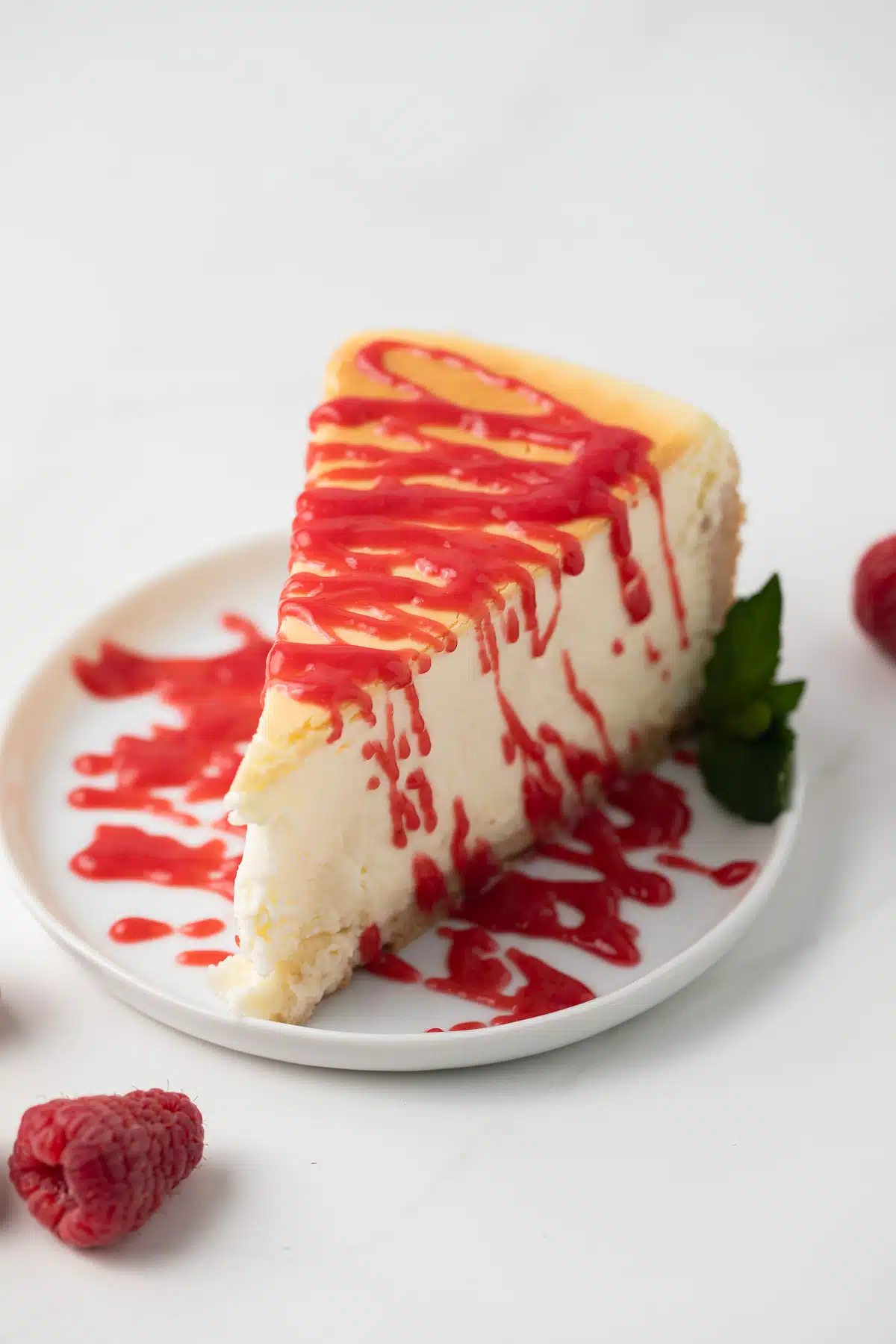 Raspberry sauce drizzled over cheesecake slice.