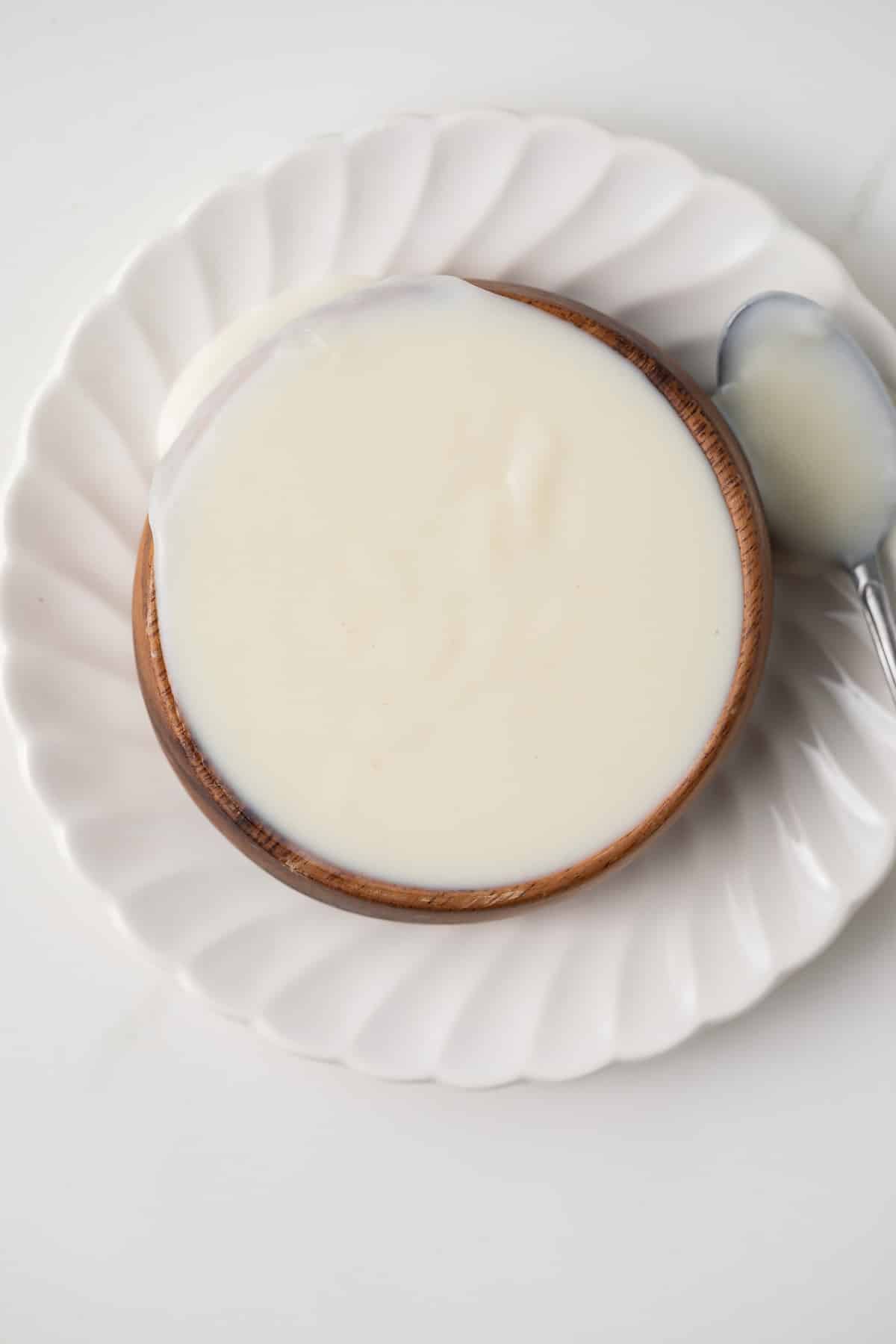 Overhead of basic White Sauce (Béchamel) in a brown bowl.