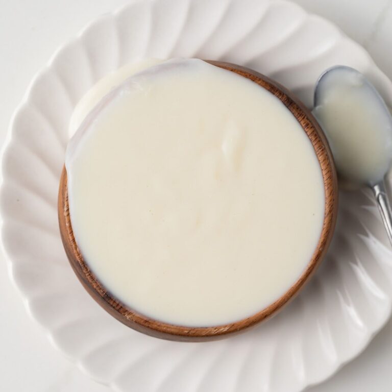 Overhead of basic White Sauce (Béchamel) in a brown bowl.