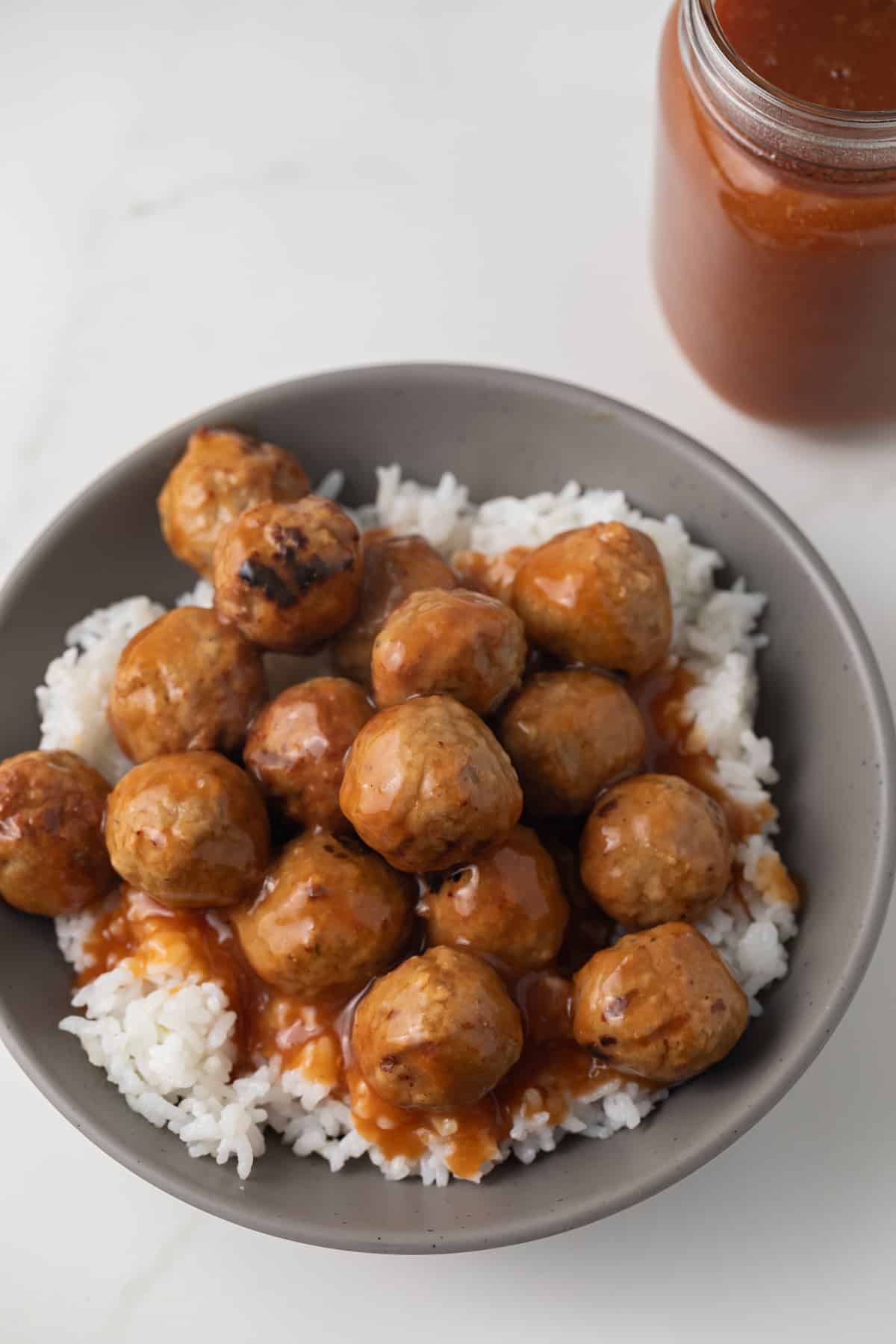 Meatballs coated in pineapple orange sauce over rice.