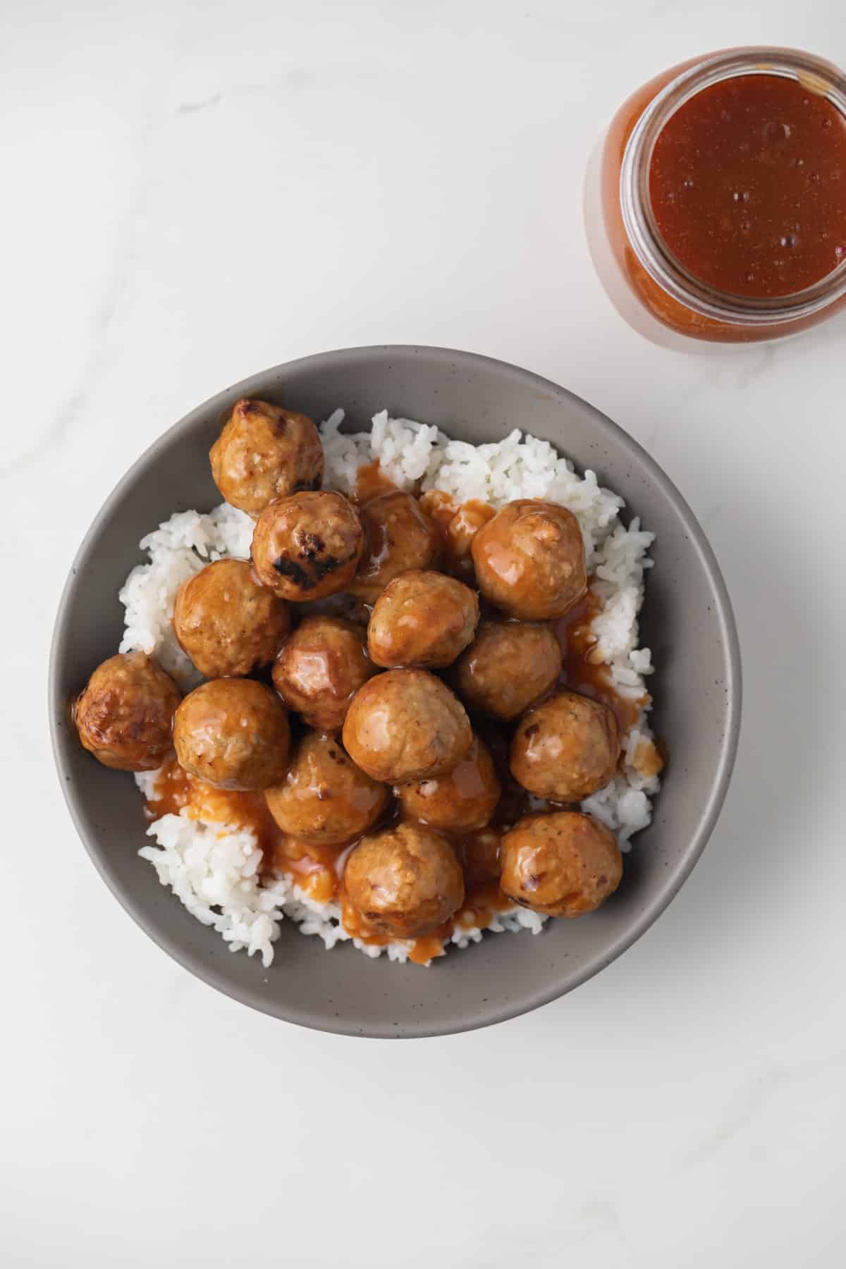 Overhead of meatballs coated in pineapple orange sauce.