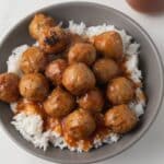 Meatballs coated in pineapple orange sauce over rice.