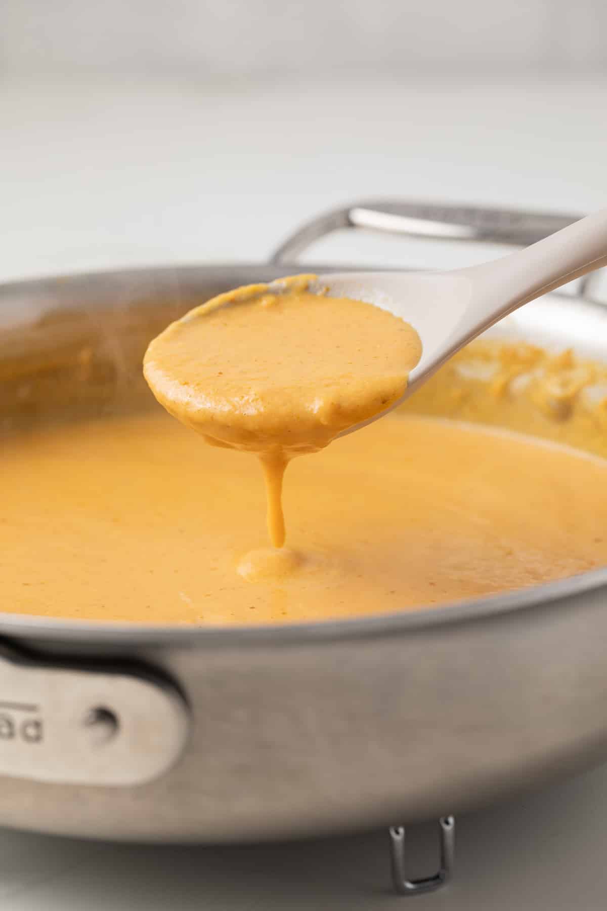 Pumpkin pasta sauce on a spoon.