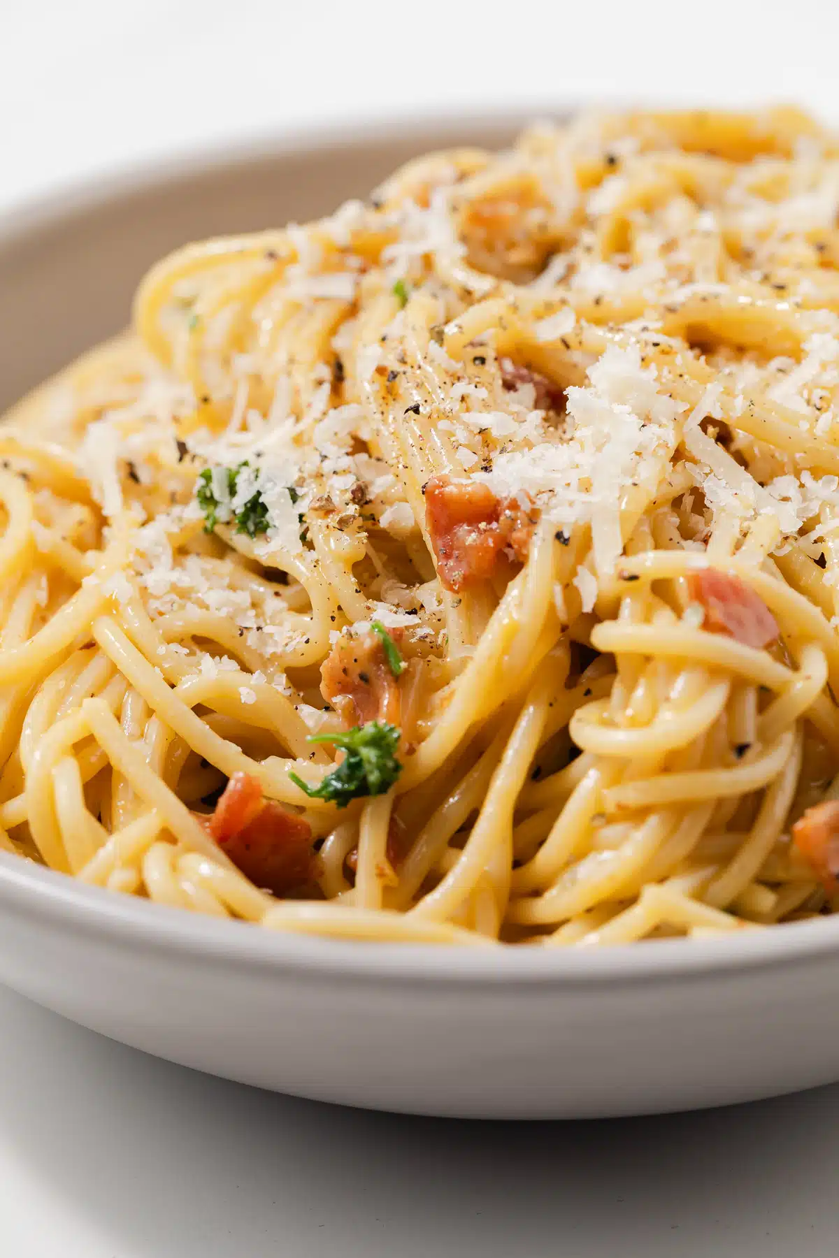 Close up of carbonara sauce over spaghetti noodles.