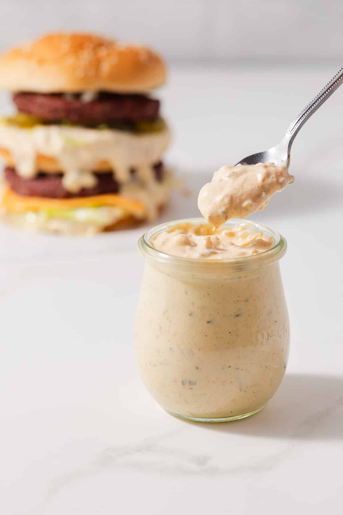 Spoon scooping out big mac sauce out of a jar.