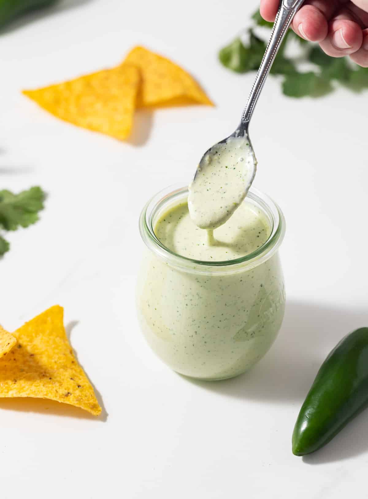Creamy jalapeno sauce spooned out of a glass jar.