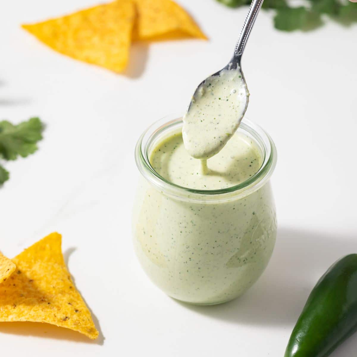 Creamy jalapeno sauce spooned out of a glass jar.