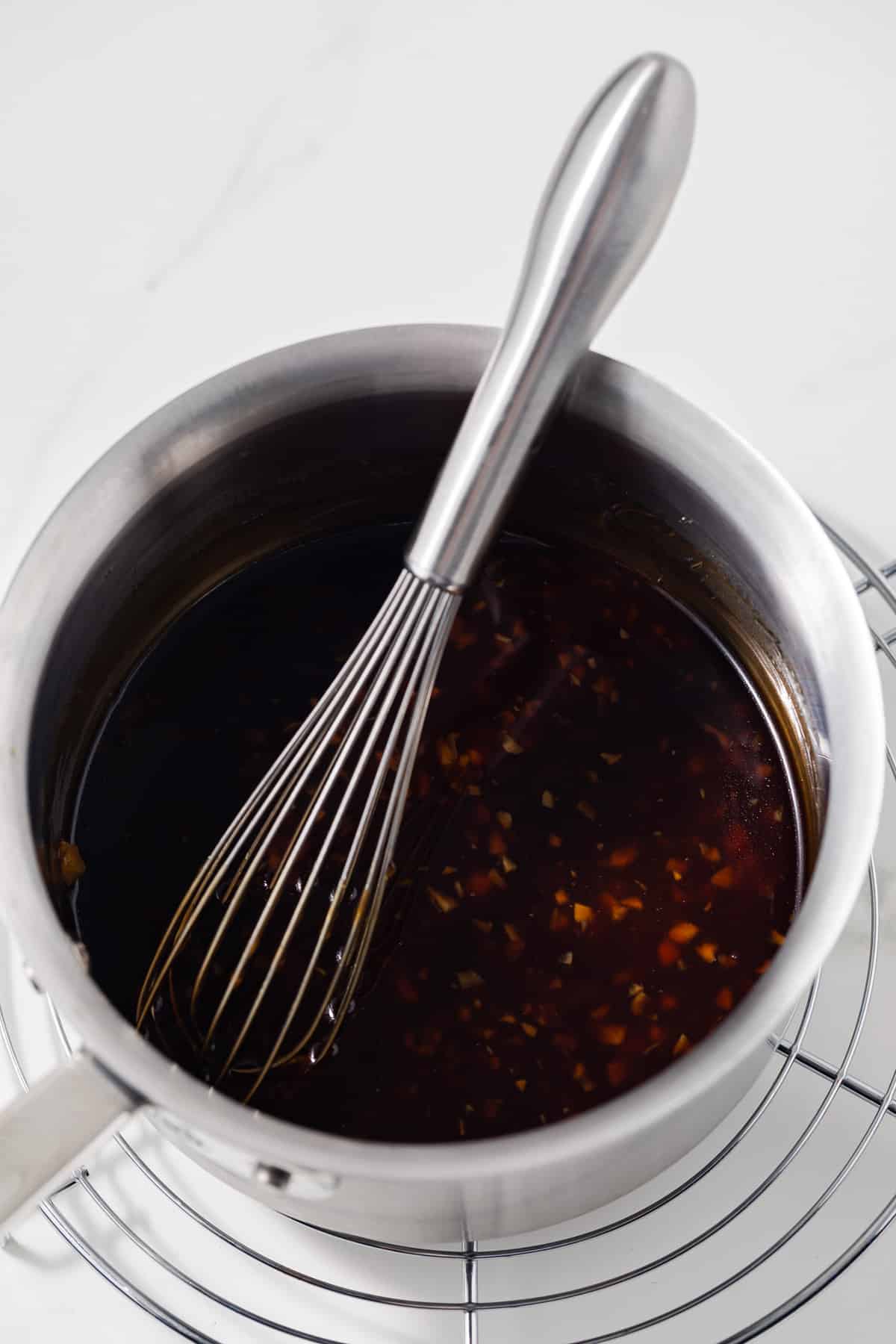 Honey garlic sauce in a saucepan with whisk.