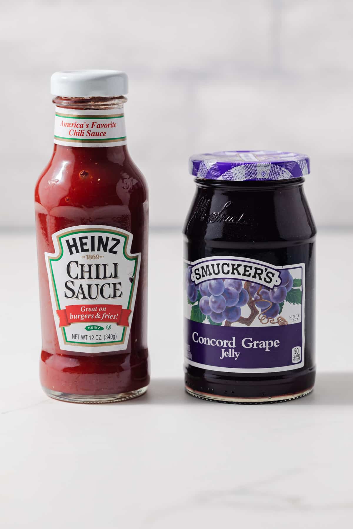 Jar of chili sauce and jar of grape jelly.