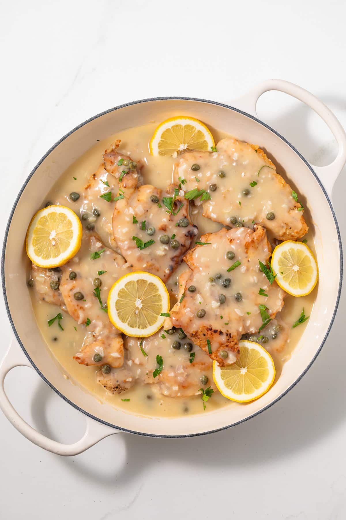 Overhead of chicken piccata in white pan.