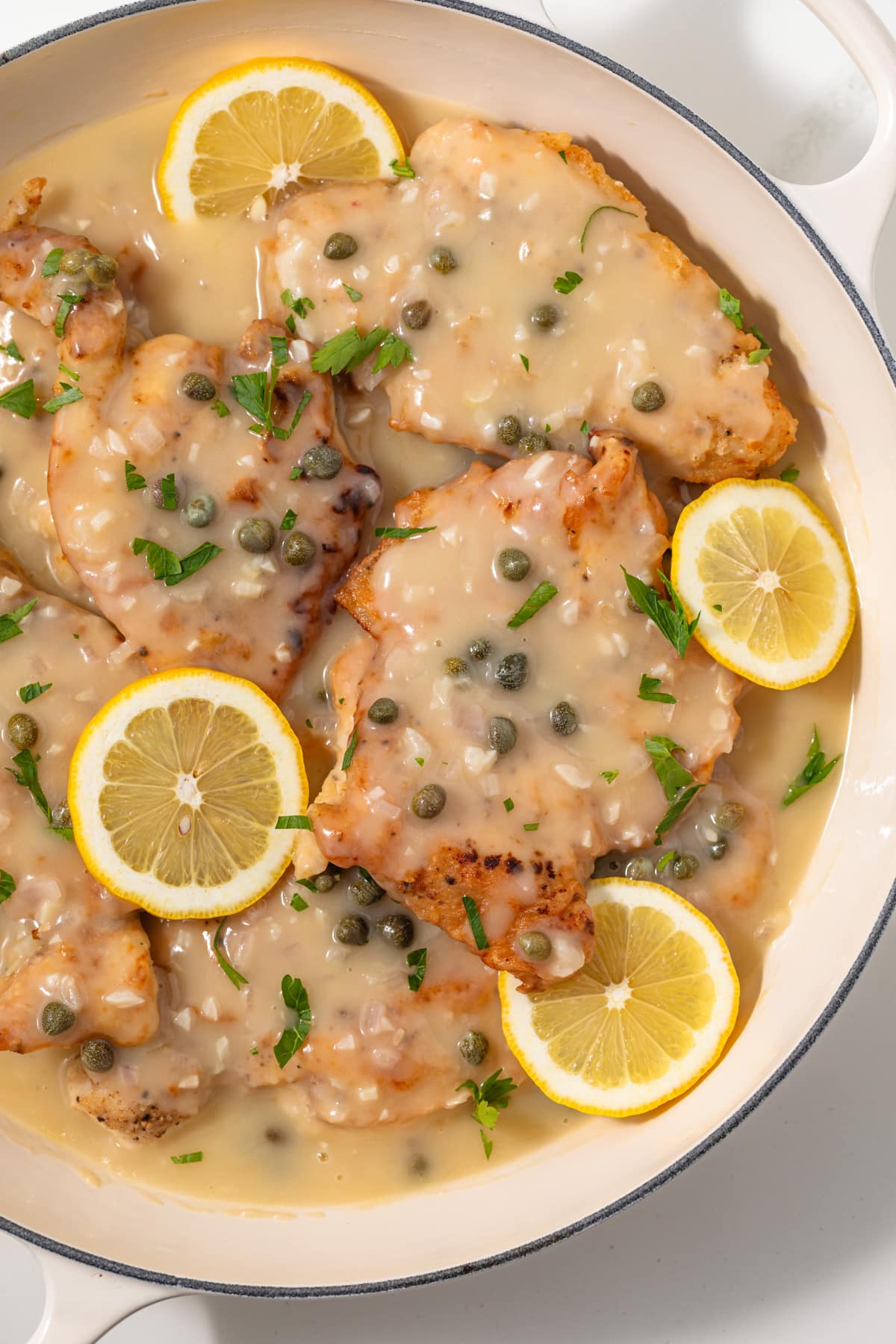 Close up of chicken piccata in white pan.