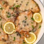 Close up of chicken piccata in white pan.