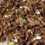 Bulgogi in topped with green onion in pan.