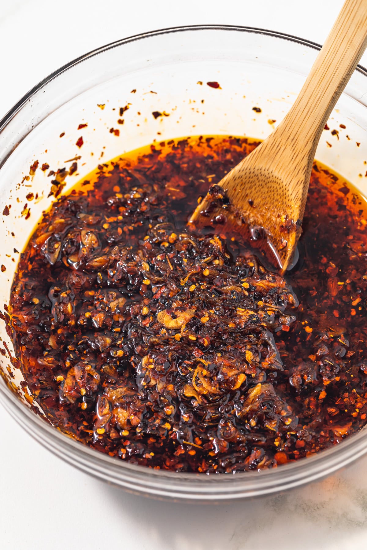 A bowl of crispy chili oil with a wooden spoon.