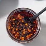 Overhead of a jar of chili crisp with a spoon inside.