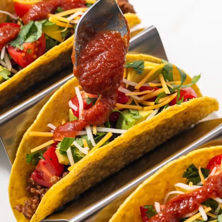 Tacos being drizzled with sauce.